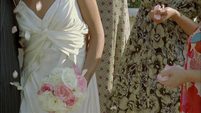 SLO MO, CU，婚礼嘉宾向新婚夫妇投掷花瓣，法国圣费尔姆城堡中部视频素材