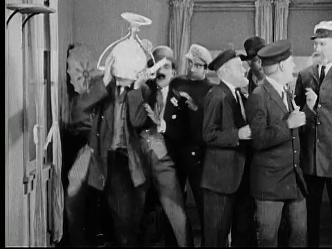 1925年B/W MONTAGE CU Cane把奖杯从架子上拉下来/奖杯花瓶掉到一个人(Andy Clyde)的头上，他挣扎着把它移开/另一个人(John J. Richardson)试图帮着把奖杯从一个人的头上移开/美国加州洛杉矶县视频素材