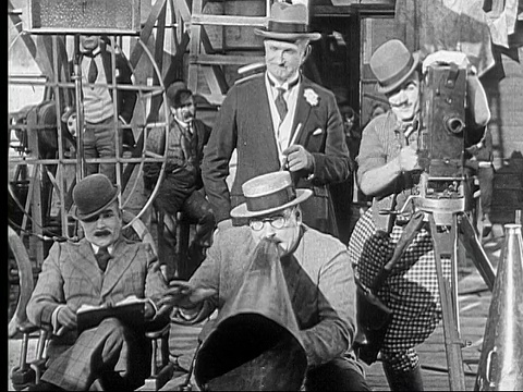 1924年，无声电影导演(弗农·登特)对着扩音器大喊，而摄影师(安迪·克莱德)正在拍摄动作，另一个人(查尔斯·默里)在观看/美国视频素材