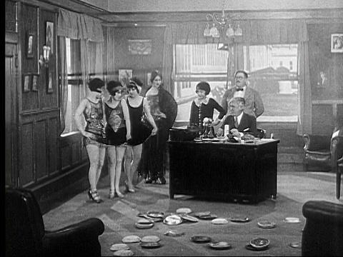 1924 B/W蒙太奇WS人们跑过混乱的办公室，跳过窗户/ MS Man (Vernon Dent)与电影工作室的负责人(Mack Sennett)交谈/ WS Showgirls进入和离开办公室，后面跟着两个男人打架/ USA视频素材