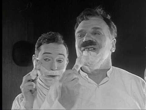 1924年B/W一名男子(哈利·兰登)在脸上涂剃须膏，旁边的另一名男子奇怪地回头看他/美国视频素材