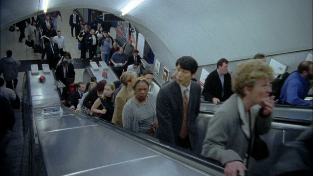 高角度中镜头拍摄的是英国伦敦地铁站搭乘自动扶梯的乘客视频下载