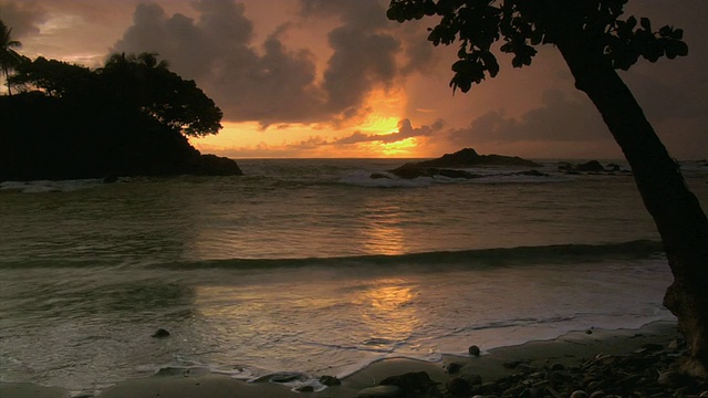日落时，海浪拍打着多米尼加海滩，背景是小岛/多米尼加，蓬塔雷纳斯省，哥斯达黎加视频下载