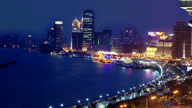 时光流逝，高角度的长镜头俯瞰外滩的天际线/驳船停靠在河里/黄昏到夜晚/上海视频素材