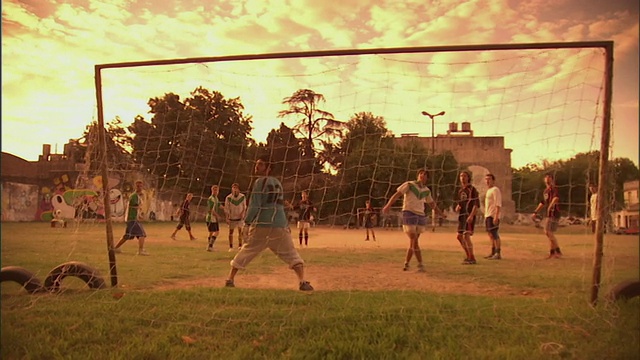 SLO MO, WS, PAN，男人在球场上踢足球在日落，布宜诺斯艾利斯，阿根廷视频素材
