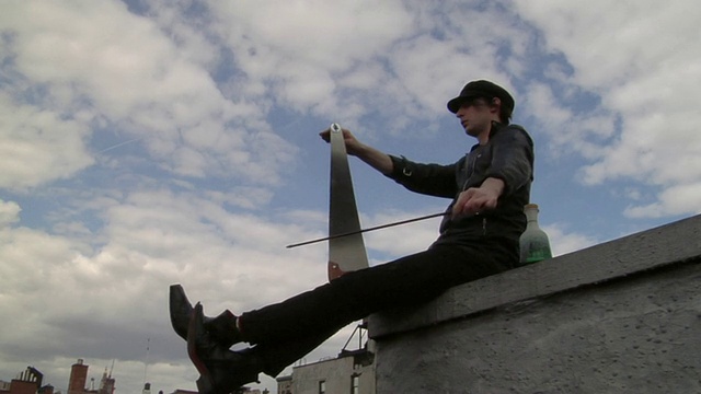 洛杉矶，一名男子坐在屋顶上玩锯子，纽约，美国视频下载