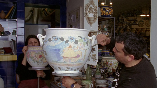 在意大利坎帕尼亚的普拉亚诺/阿马尔菲海岸的工作室中，中景的工匠在画陶瓷花瓶视频下载