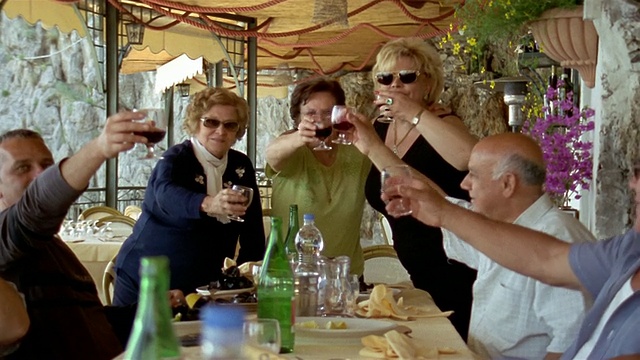 中景镜头:意大利阿马尔菲海岸，普拉亚诺，人们举起红酒，举杯庆祝视频下载