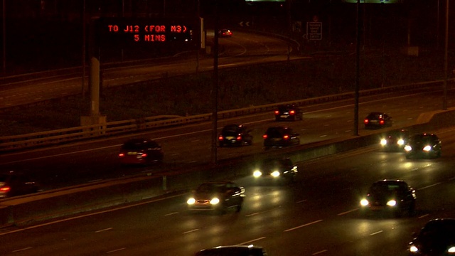 英国伦敦，M25高速公路夜间行驶在路口标志下方视频素材