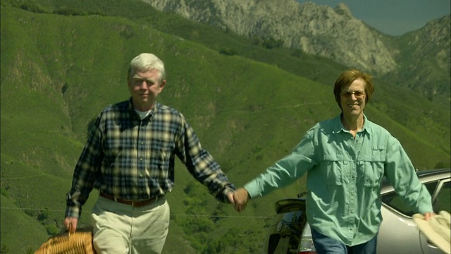 在美国加州大苏尔的山景中，老夫妇带着野餐篮离开汽车视频下载