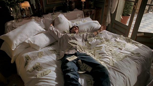 慢镜头男人亲吻床上的一把钞票/向后倒，把钞票扔到空中/钞票漂浮视频下载
