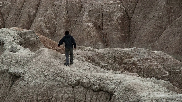 WS，在Badlands国家公园的岩石上行走的人的后视图，南达科他，美国视频素材