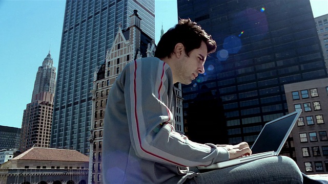 在一个阳光明媚的日子里，在曼哈顿金融区/纽约市用笔记本电脑工作的年轻男子视频素材