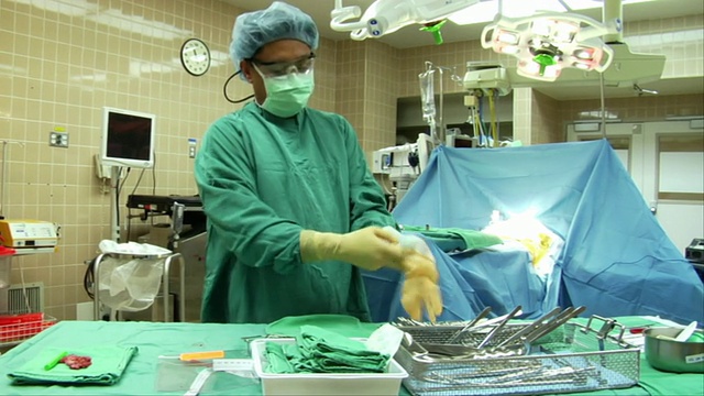 美国加州伯克利，护士戴上无菌手术手套，协助外科医生站在手术室视频下载