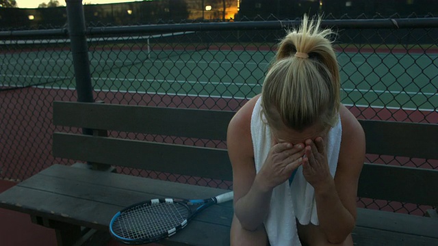 美国加州圣巴巴拉，一名年轻女子坐在网球场的长椅上视频素材