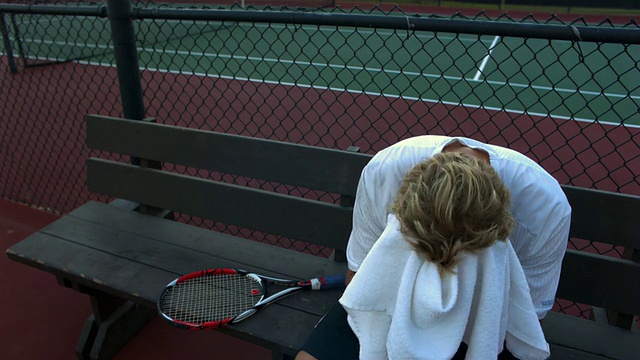 美国加州圣塔芭芭拉，一名沮丧的年轻人坐在网球场的长椅上视频素材