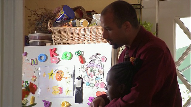 中镜头的父亲与女儿和儿子在冰箱前交谈视频素材