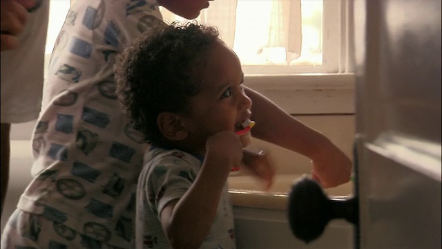中等镜头倾斜的蹒跚学步，哥哥和父亲在早上刷牙视频素材