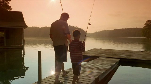 宽镜头的父亲和儿子拿着鱼竿到码头的尽头/克拉克斯维尔，乔治亚州视频下载