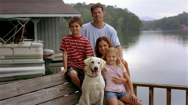 中等拍摄的肖像家庭与宠物拉布拉多猎犬坐在码头上视频下载