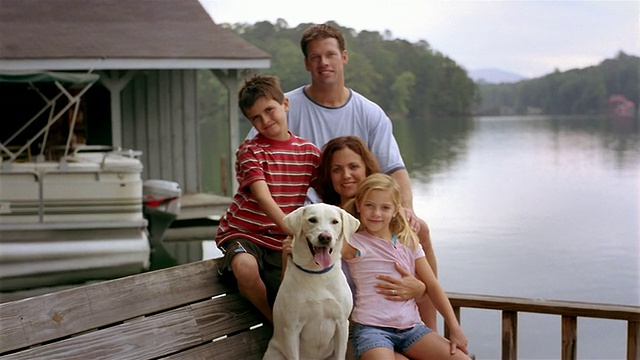 中等拍摄的肖像家庭与宠物拉布拉多猎犬坐在码头上视频下载