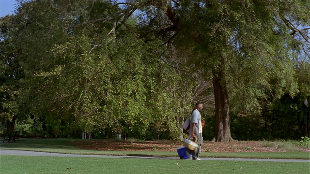 长镜头的父母带着野餐篮和冷却器穿过公园+孩子们在前面的路径/亚特兰大视频下载