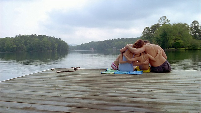广角镜头后的家庭坐在码头上的湖/拥抱视频下载