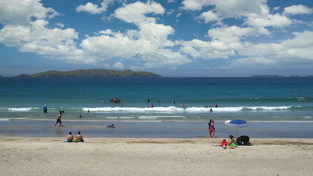 阳光明媚的一天，新西兰北国海滩上的人们视频下载