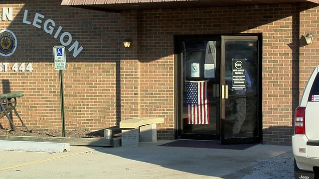 美国俄亥俄州新诺克斯维尔市，一对夫妇通过一扇印有美国国旗的门进入大楼视频素材