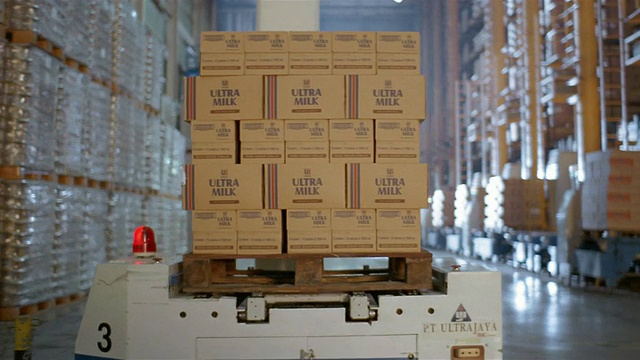 在牛奶工厂的仓库里，中等大小的盒子在机器人托盘上移动视频素材
