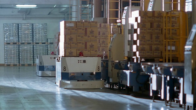 在牛奶工厂的仓库里，中等大小的盒子被装载到机器人托盘上视频素材