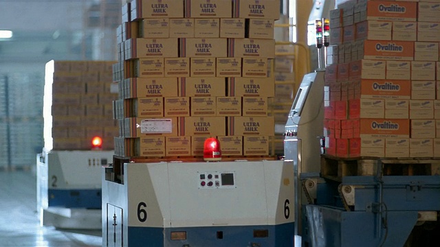 在牛奶工厂的仓库中，由机器人托盘移动的中拍摄的盒子视频素材