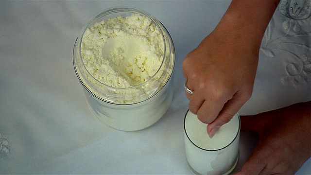 高角度近距离观察奶粉被从罐中舀出并与水混合视频下载