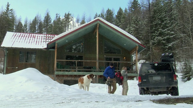 一对夫妇和一只圣伯纳德犬来到美国蒙大拿州白鱼山的小木屋视频素材
