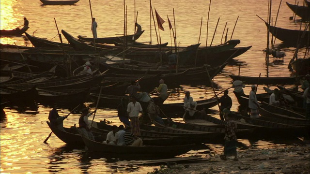 日落时分，孟加拉国达卡，人们在河岸上乘船视频素材