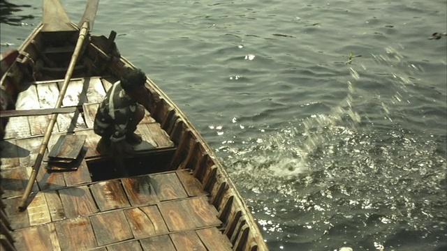 孟加拉国达卡，男人们正在排空停泊在河岸上的船只上的水视频素材