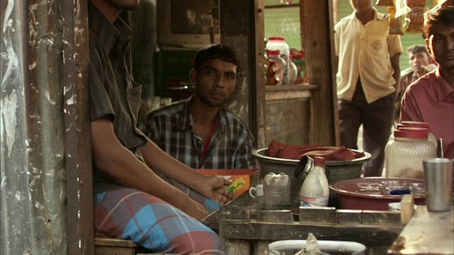 孟加拉国，Mawna，一名男子正在洗碗里的玻璃，旁边坐着其他男子视频素材