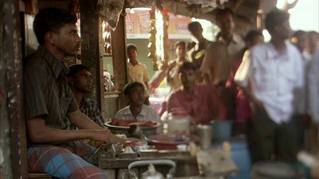 MS, SELECTIVE FOCUS, Man making tea in tea shop, people standing in门口排队，Mawna，孟加拉国视频素材