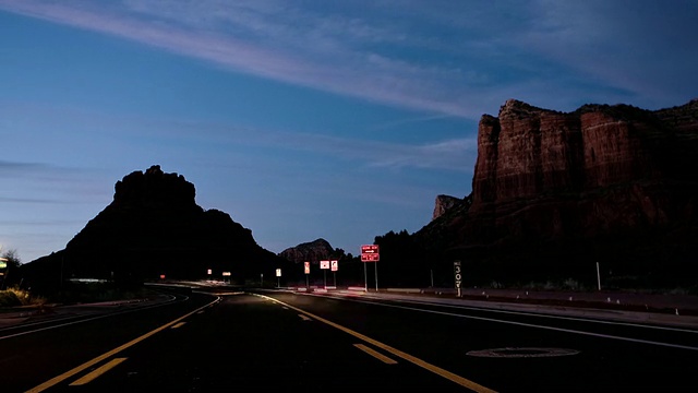美国亚利桑那州塞多纳，夜间红色岩石之间的乡村公路交通视频下载
