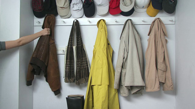 美国纽约斯卡伯勒的衣帽间里，一名女子用手将外套挂在衣帽间的挂钩上视频下载