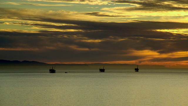 日落时，美国加利福尼亚州圣巴巴拉的海洋中石油钻塔的剪影视频素材