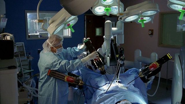 在机器人手术过程中，医生坐在控制台和妇女摆机器人手臂视频下载