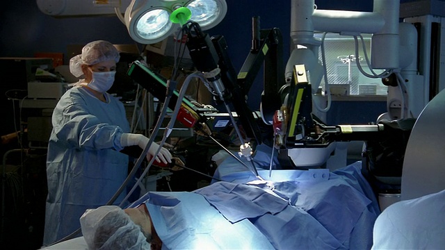 在机器人手术中，医生坐在控制台和妇女定位机器人手臂视频下载