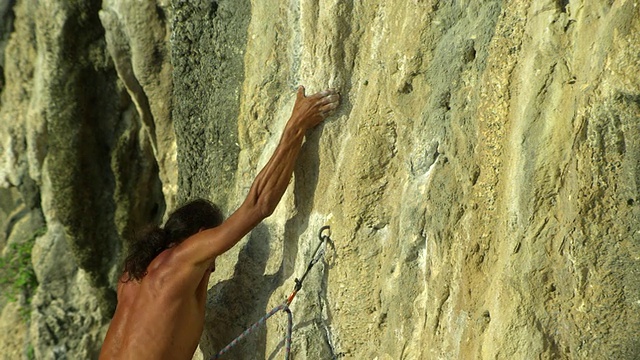 男子赤足攀爬岩壁，将绳索扣入钩环，攀登泰国甲米视频素材
