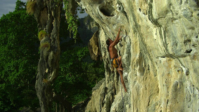 泰国甲米，男子赤足攀爬岩壁，将绳索扣入钩环，手浸在白垩袋中，攀爬视频素材