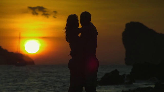 一对夫妇的剪影在热带海滩上拥抱在日落，甲米，泰国视频素材