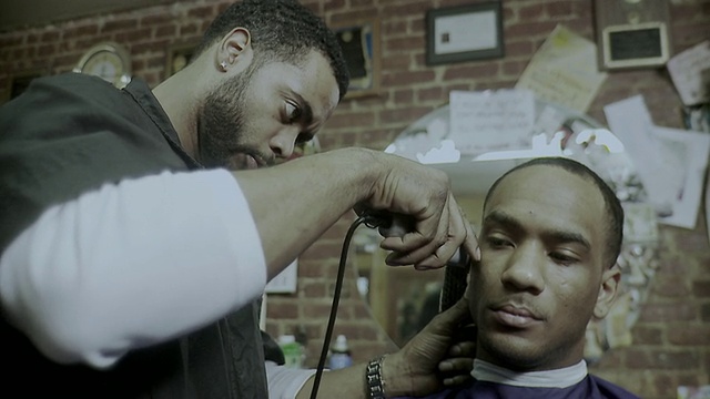 美国纽约州布鲁克林区的一家理发店里，一位理发师正在给一位男士理发视频素材