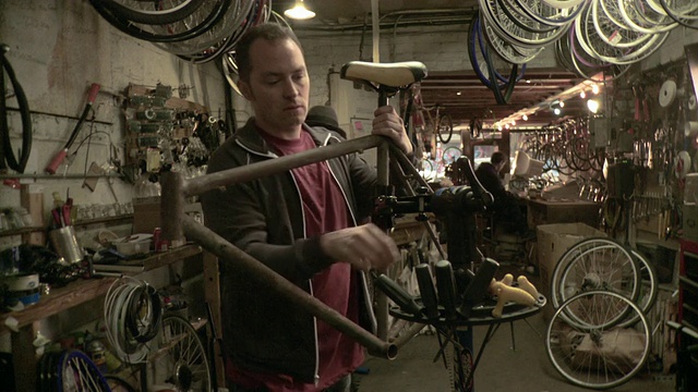 MS Man在美国纽约州布鲁克林市的自行车车间将旧自行车架安装到车架上，将车座拧到车座上视频下载