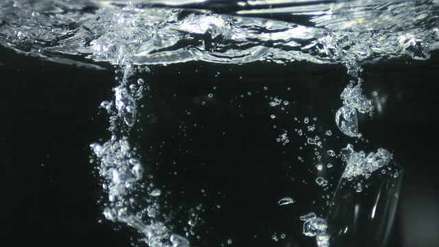 SLO MO CU Studio拍摄的黑色背景下的酒杯落入水中视频素材