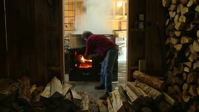 美国新罕布什尔州北康威，一名工人在糖舱里装载木材，准备在锅炉下用树液点火视频下载